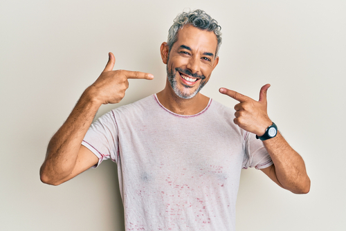 Middle age grey-haired man wearing casual clothes smiling cheerful showing and pointing with fingers teeth and mouth